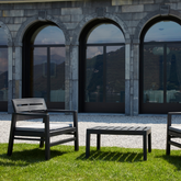 Conjunto composto por duas cadeiras com braços e encosto de apoio, acompanhadas de almofadas no assento, e uma mesa baixa IPAE PROGARDEN. Exibido em ambiente exterior.